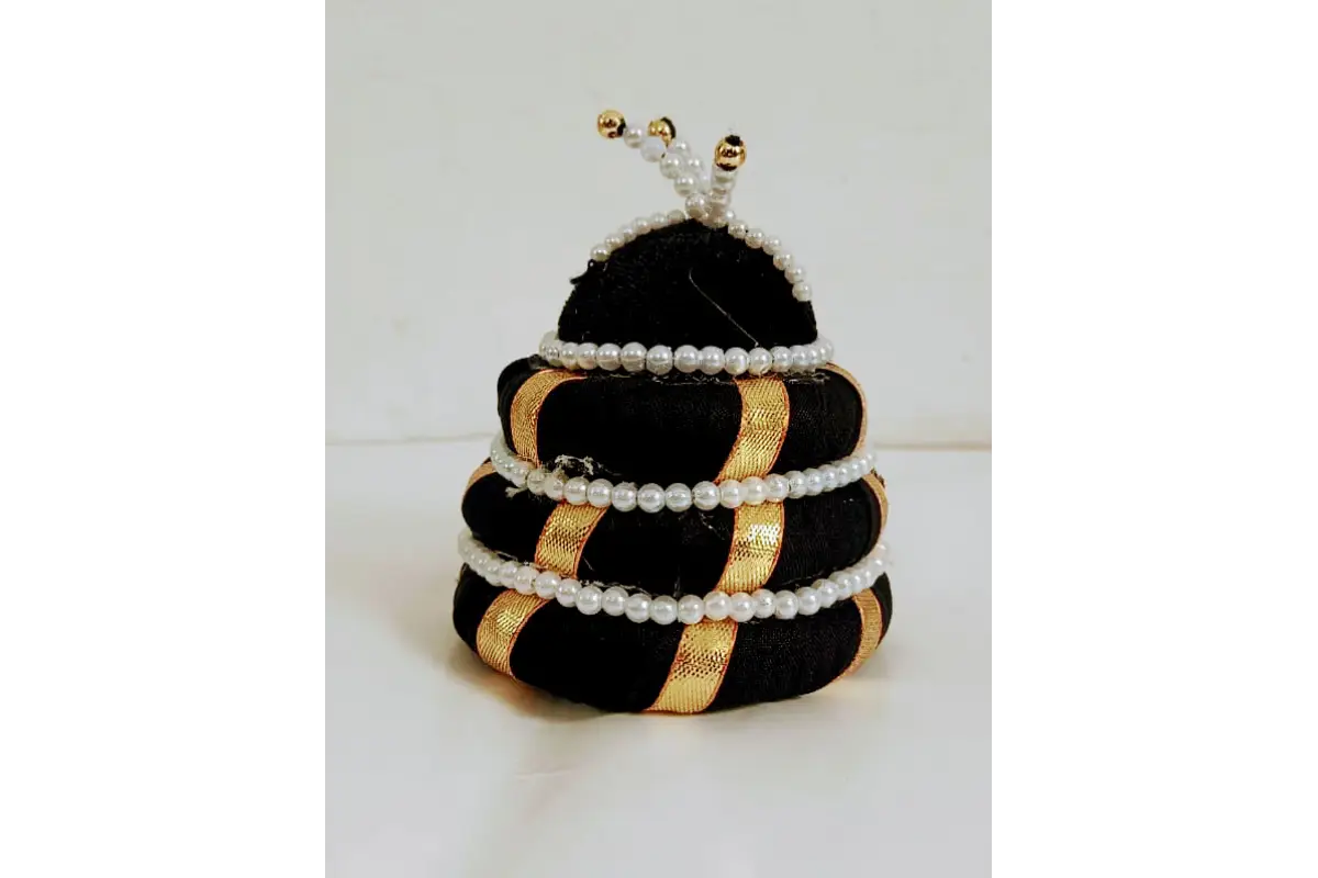 Decorative item resembling a beehive with black, gold, and white colors on a white background