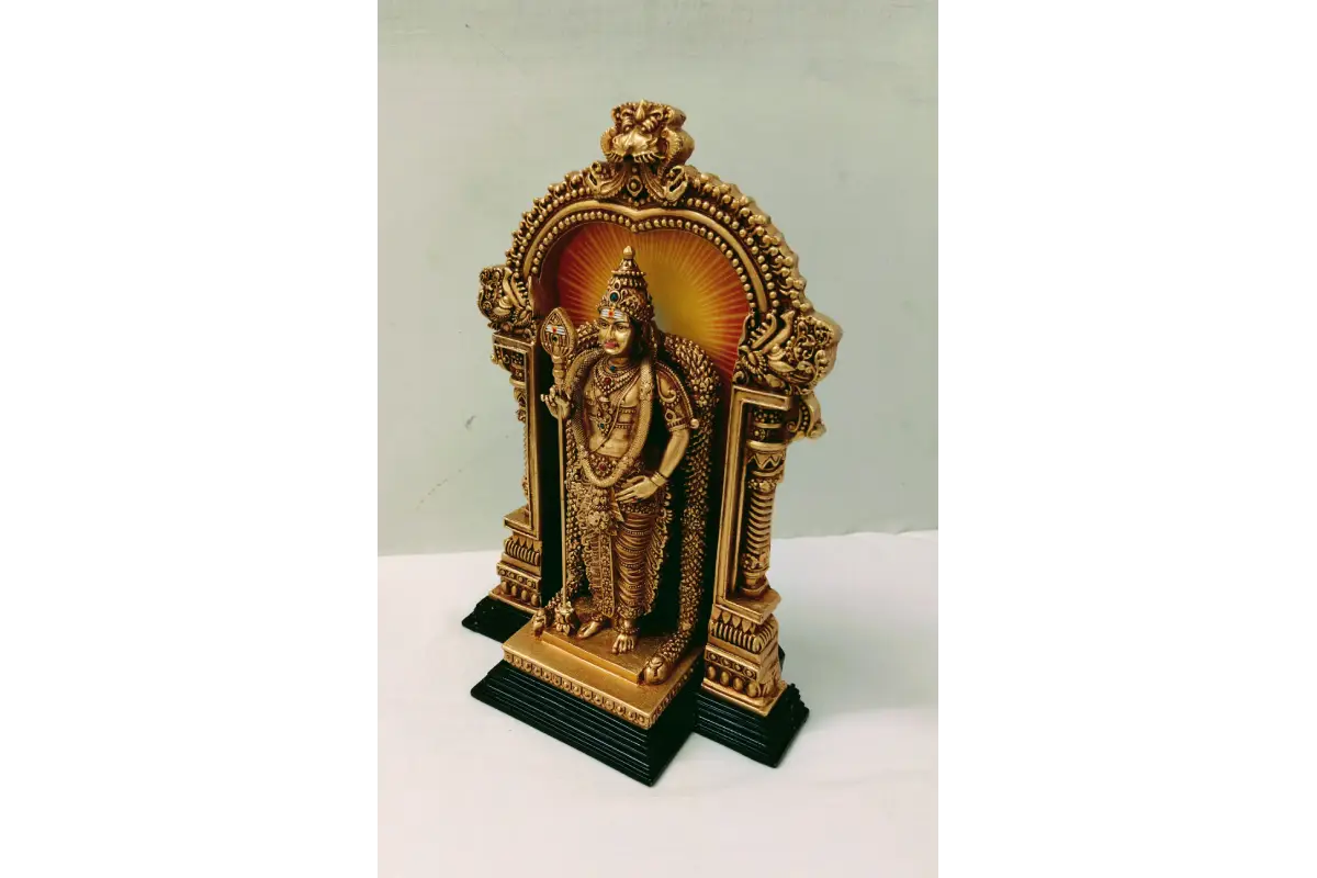 Small golden statue in a decorative stand on a white background