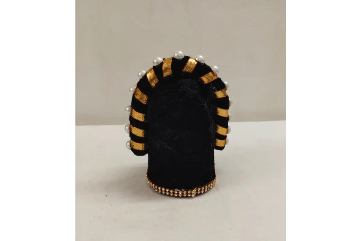 Black and gold decorative item with pearls on a white surface