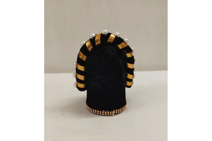 Black and gold decorative item with pearls on a white surface