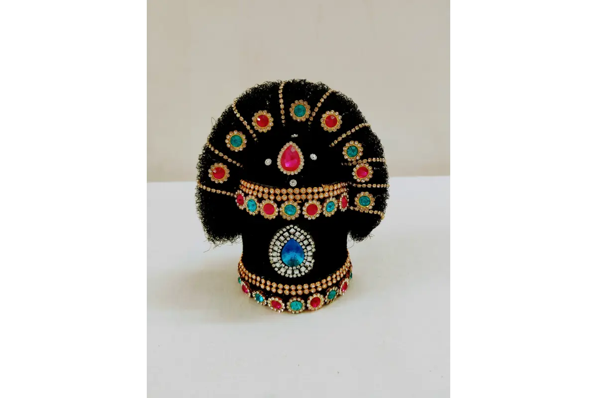 Decorative black object with colorful gemstones on a white surface