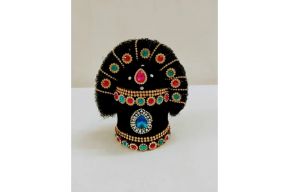 Decorative black object with colorful gemstones on a white surface
