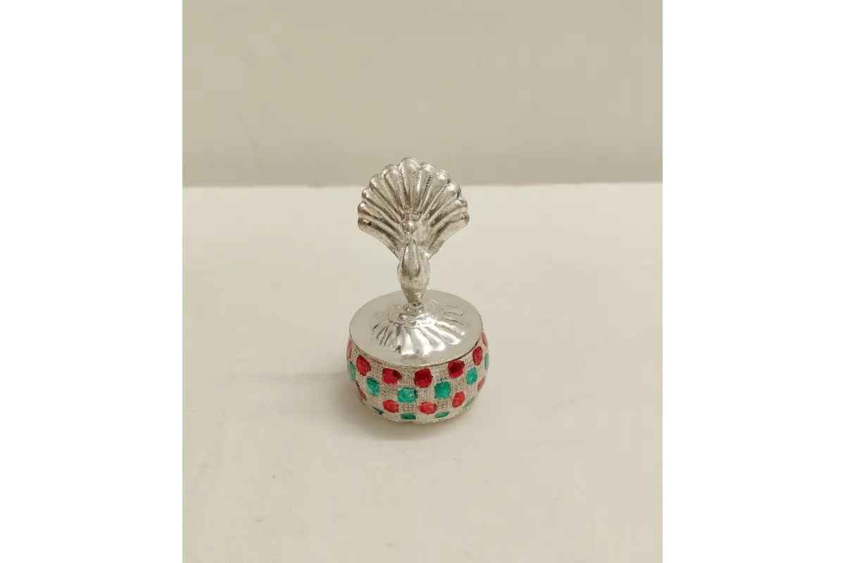 Silver peacock kumkum box placed as a decorative element in a home pooja mandir