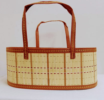 A woven straw basket tote bag with brown fabric handles and decorative braided trim, shown against a plain white background.