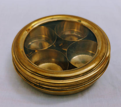 Brass Anjarai Petti filled with spices like mustard, turmeric, and cardamom in a kitchen setting