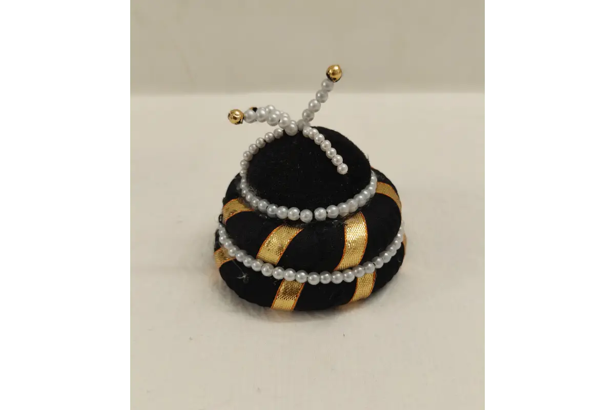 Decorative object resembling a beehive with black, gold, and white colors on a light gray background.