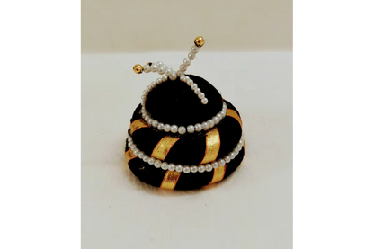 Decorative item resembling a beehive with a bee on top, featuring black, gold, and white colors.