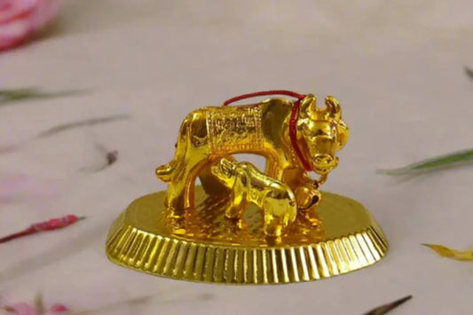 Traditional metal Kamadhenu cow and calf statue on decorative base for home pooja room.