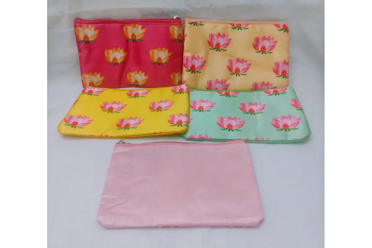 Close-up view of vibrant pink lotus print on soft yellow satin fabric pouch