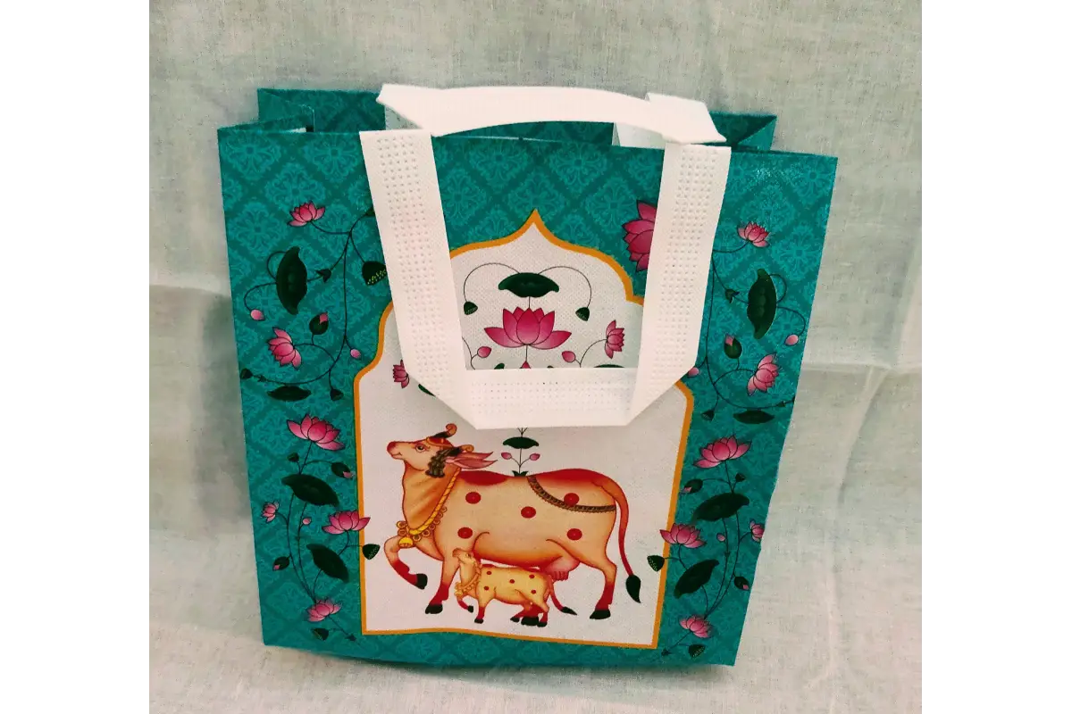 Close-up view of intricate Pichwai lotus flower and divine cow print on fabric gift bag