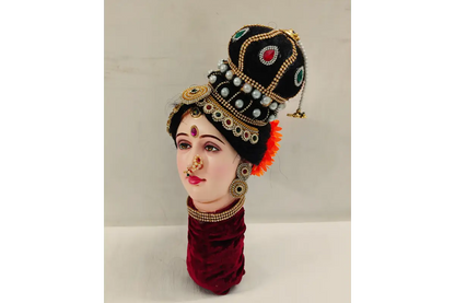 Traditional headpiece with jewelry on a mannequin head against a neutral background