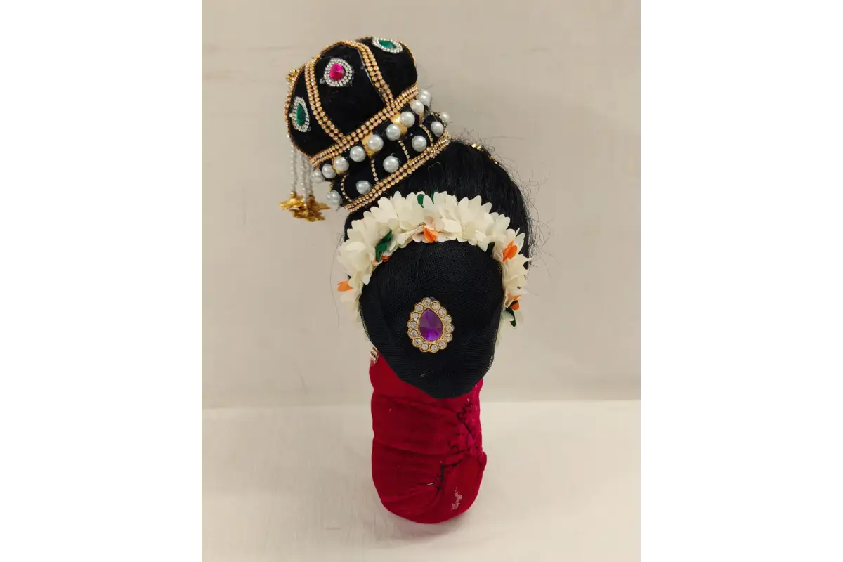 Decorative item resembling a traditional figure with a crown and red garment on a light background