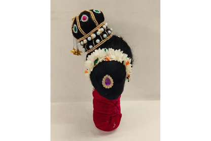 Decorative item resembling a traditional figure with a crown and red garment on a light background