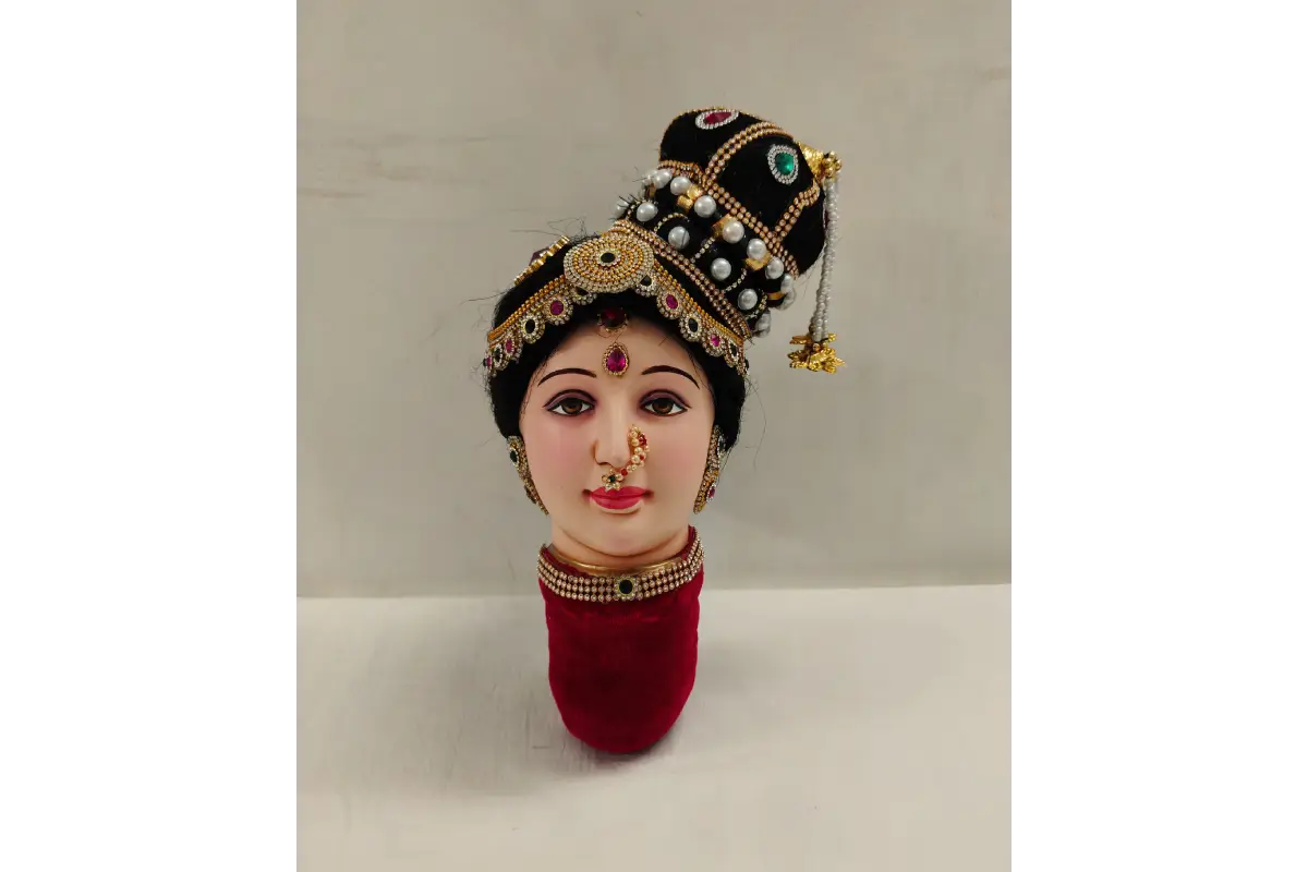 Traditional Indian doll head with jewelry and a headdress on a white background