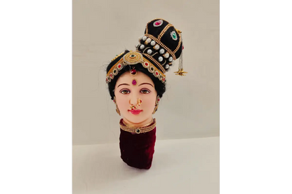 Traditional headpiece with pearls and gemstones on a mannequin head against a neutral background