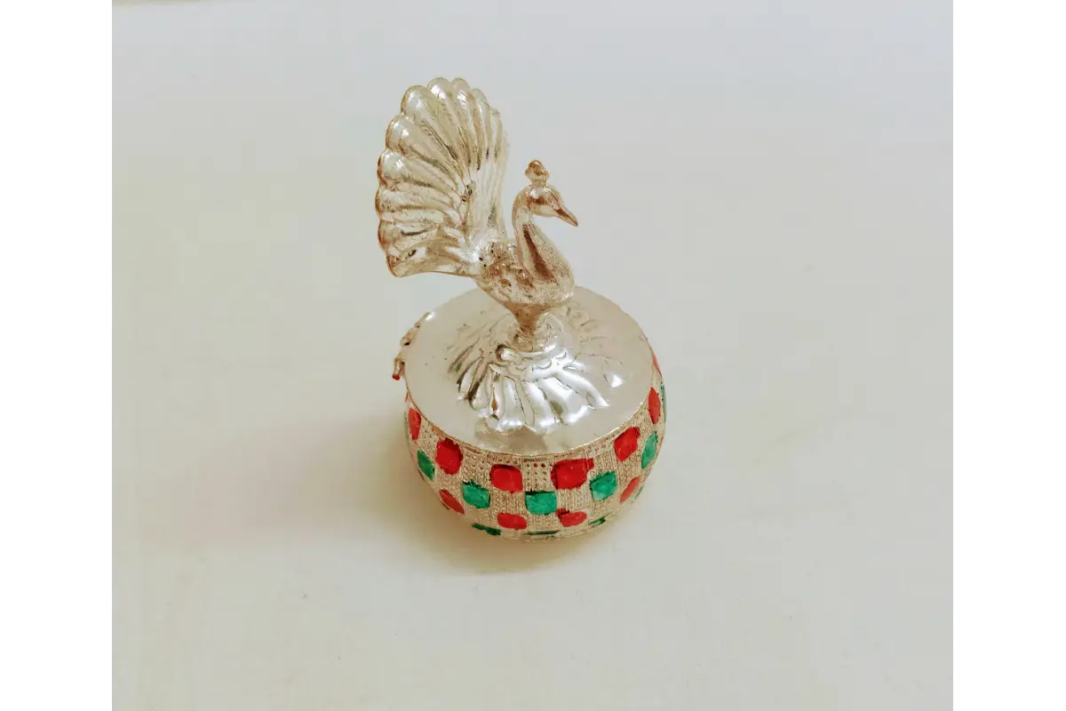 Close up of German silver peacock sindoor box with green and red enamel work