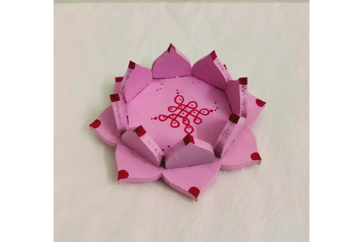 Wooden lotus diya stand placed at the center of a colorful flower rangoli for Diwali decor